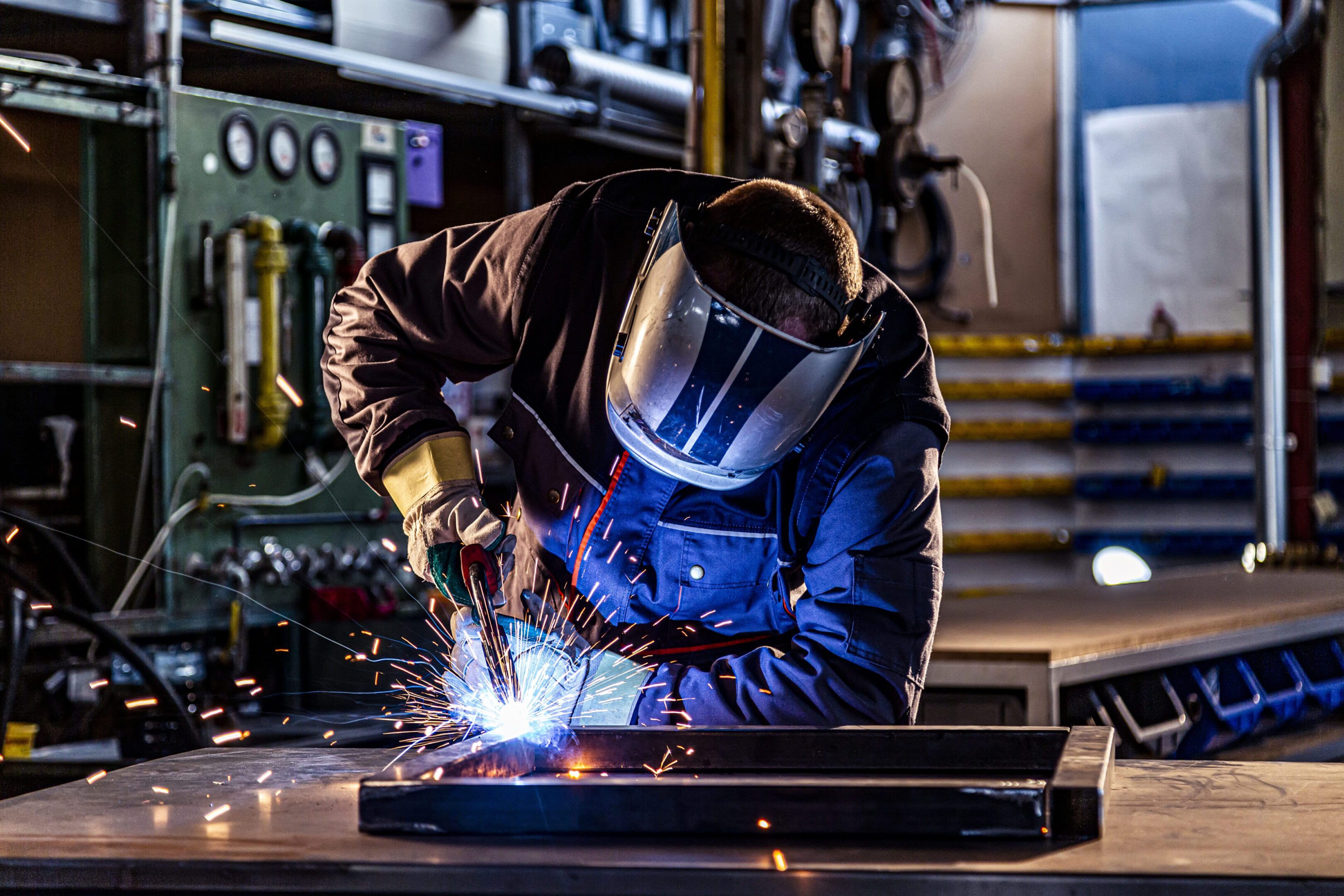Person welding metal in industrial workshop.