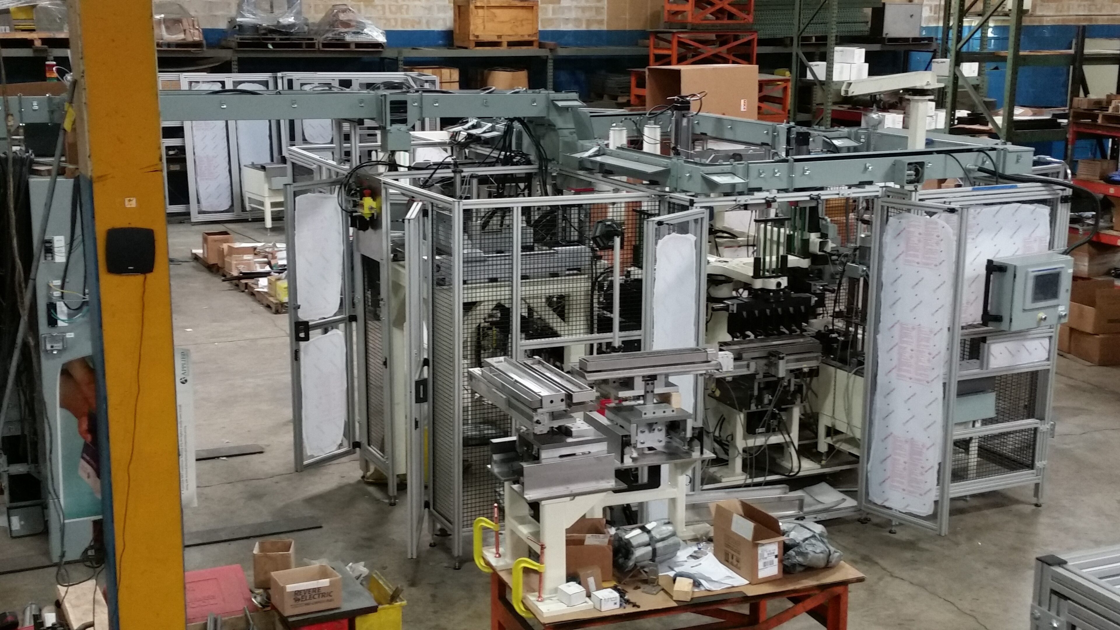 Industrial machinery setup in a warehouse with metal frameworks and conveyor components.